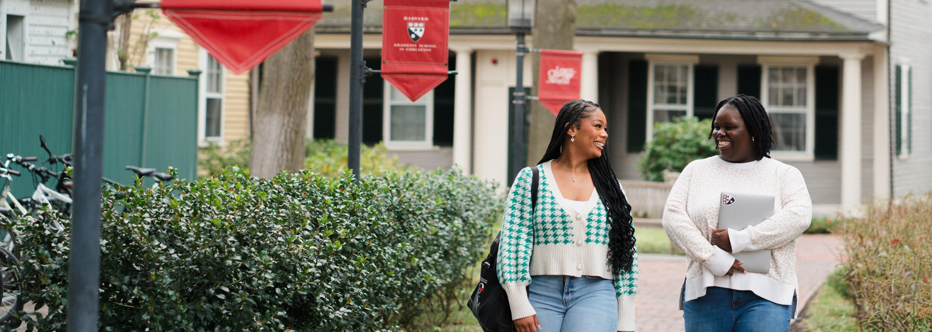 Two Students walk the path in front of Nichols House